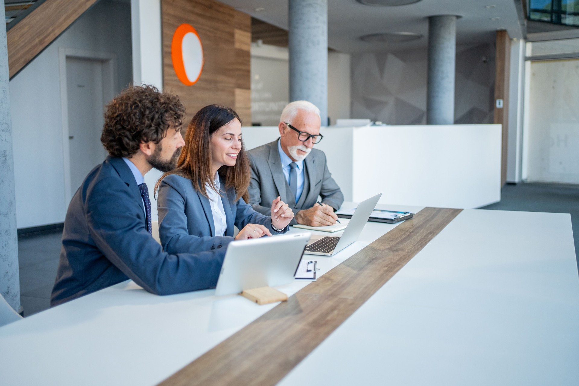 Businesspeople working together at office desk using digital tablet and laptop